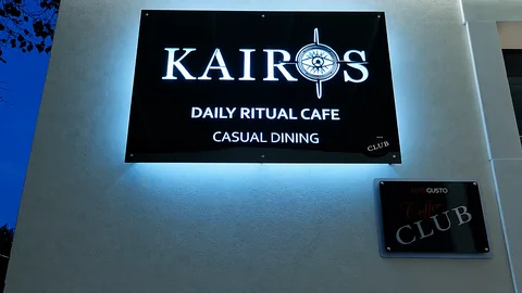 Insegna luminosa Kairos Daily Ritual Cafe al crepuscolo